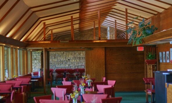 Restaurant interior with red chairs and wooden beams.