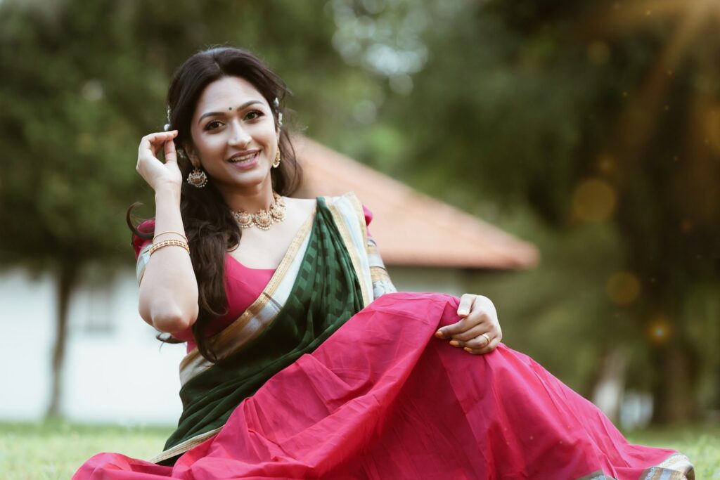 A woman in a pink and green sari sits outdoors.