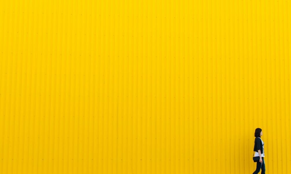 woman wearing black top standing near yellow wall