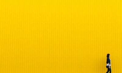 woman wearing black top standing near yellow wall