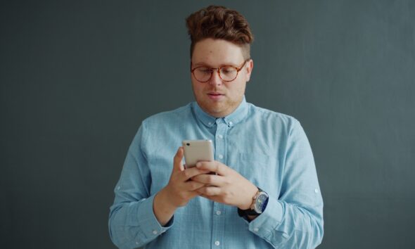 Man in glasses looking at his phone.