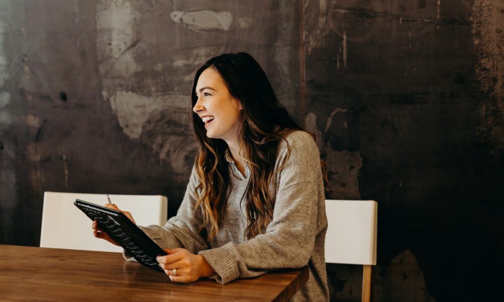 woman sitting around table holding tablet