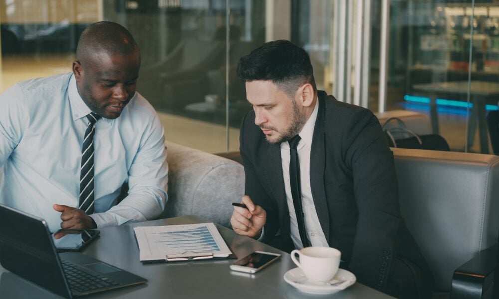 Two businessmen reviewing documents at a table.