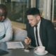 Two businessmen reviewing documents at a table.