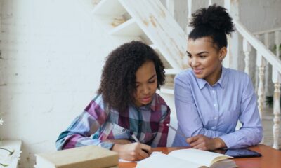 A woman helps a girl with her homework.