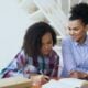 A woman helps a girl with her homework.