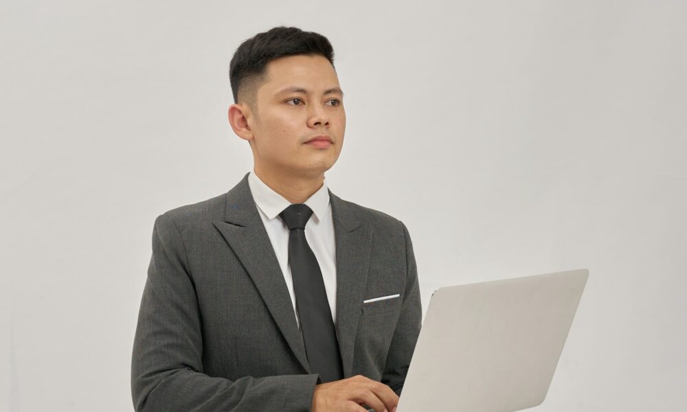 A businessman is holding a laptop and looking up.