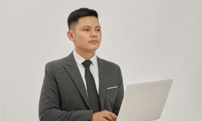 A businessman is holding a laptop and looking up.