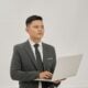 A businessman is holding a laptop and looking up.