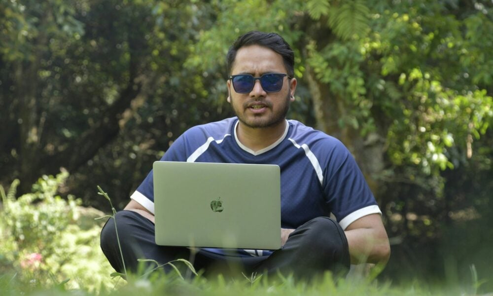 a man sitting in the grass with a laptop