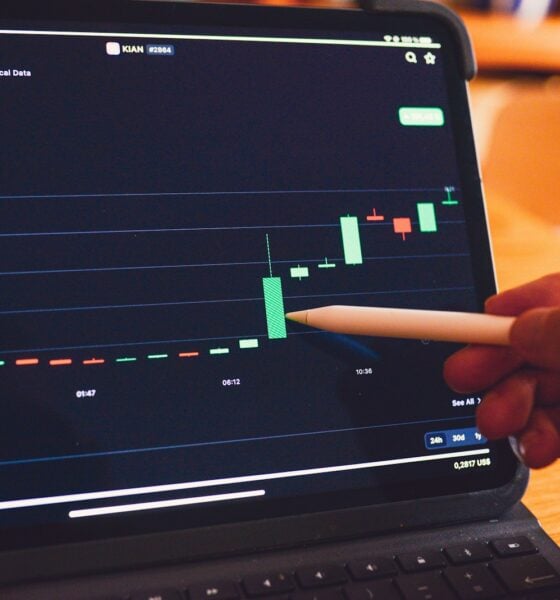 a person is holding a pencil in front of a laptop
