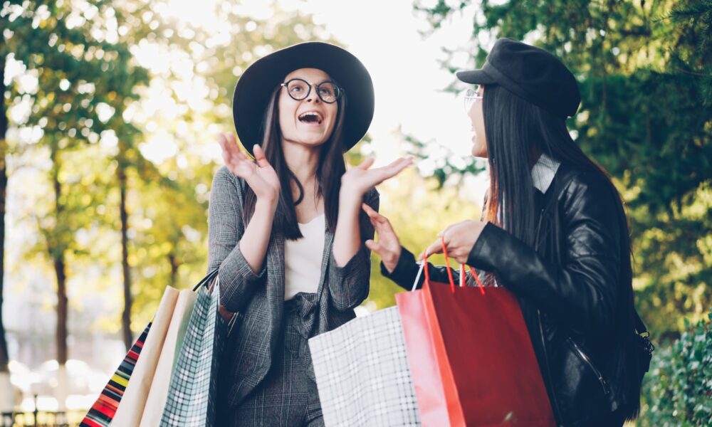 Two women with shopping bags in a park