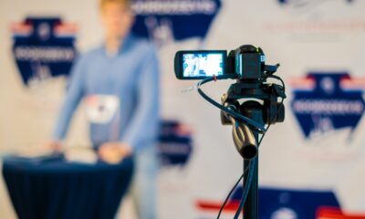 a person standing behind a microphone with a cell phone on a tripod