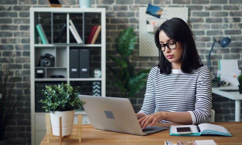 a woman sitting at a desk using a laptop computer