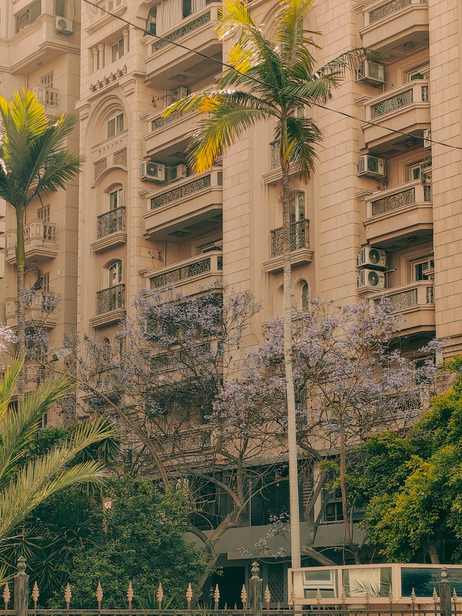 Elegant residential building facade with palm trees and lush greenery.