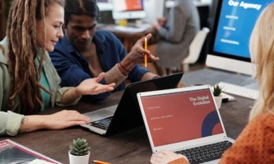 Diverse team collaborating with laptops in a modern office setting, discussing digital evolution.