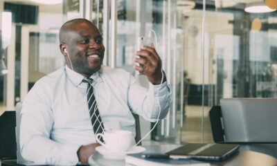 Man in shirt and tie with headphones using phone.
