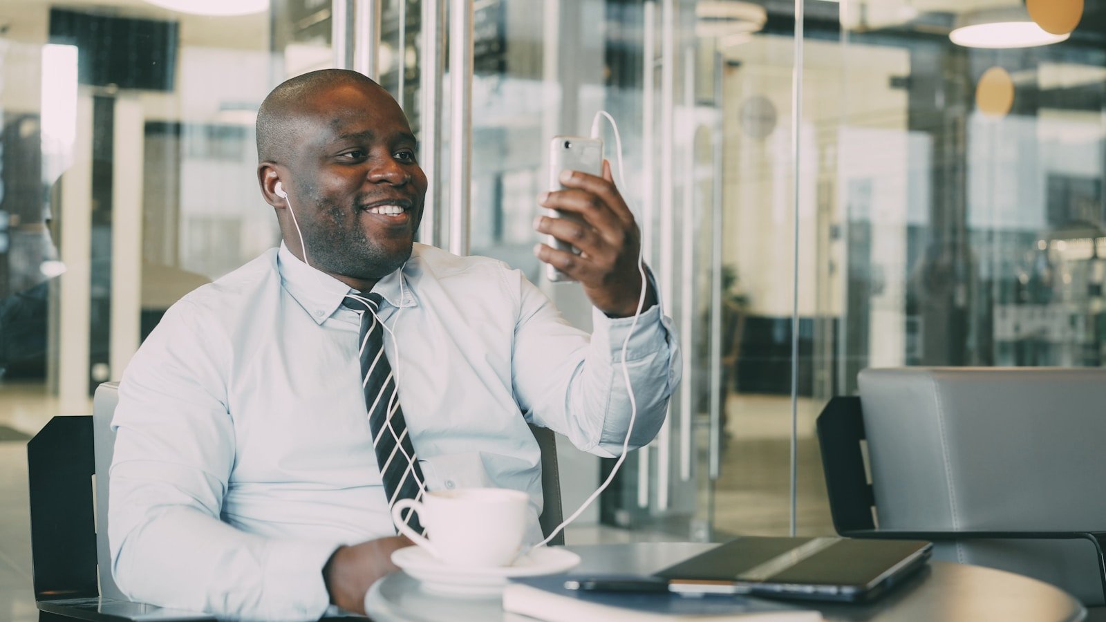 Man in shirt and tie with headphones using phone.