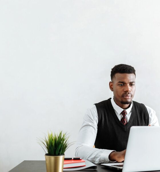 Professional man sitting at a desk working on a laptop in a modern office environment.