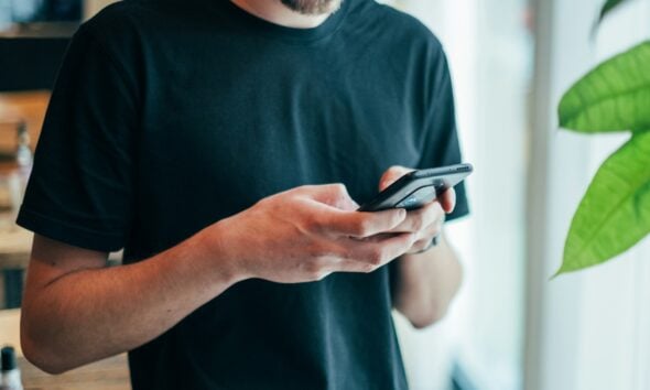 man in black crew-neck top using smartphone