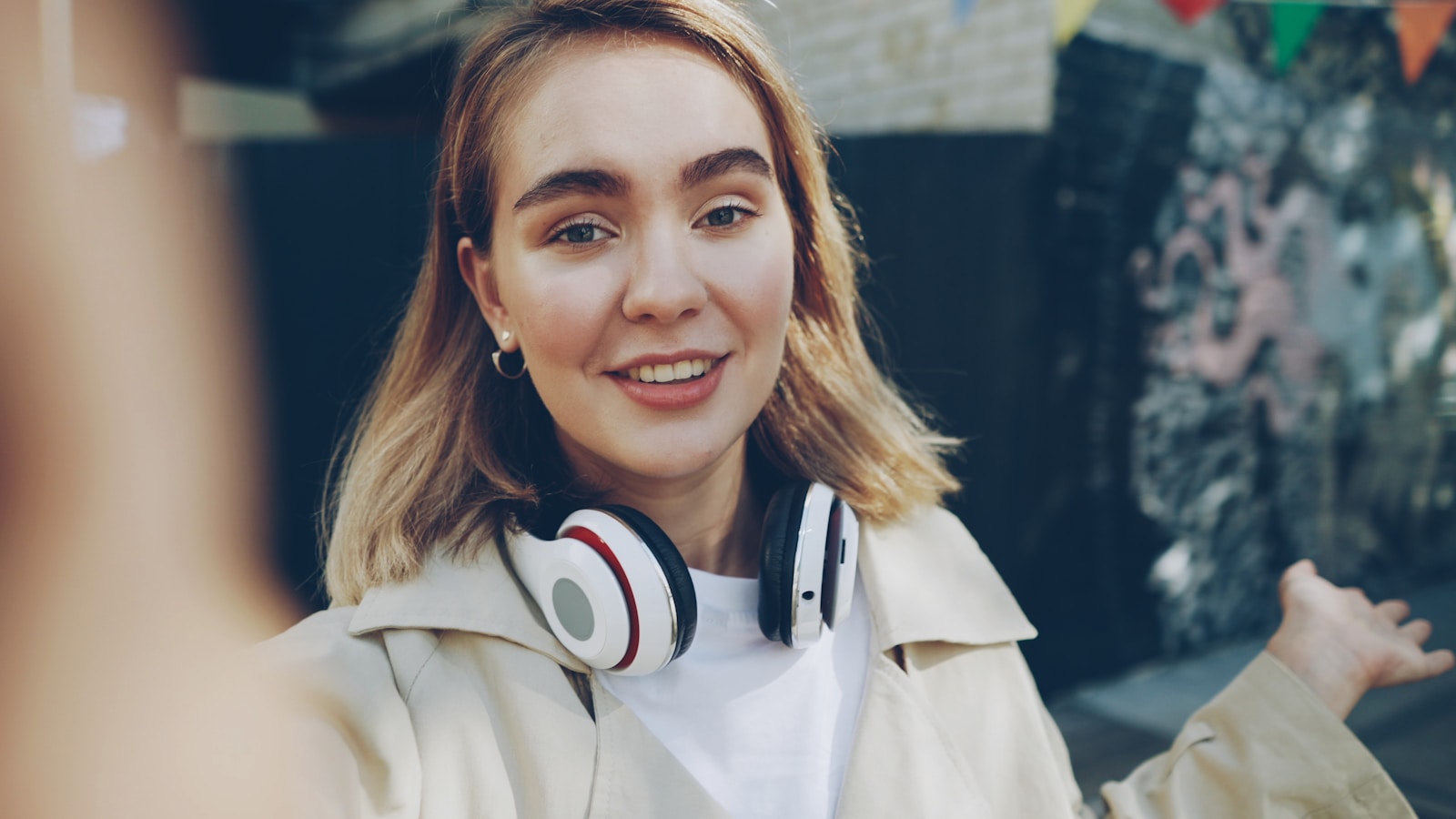 Young woman with headphones talking outdoors