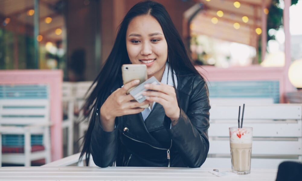 Young woman using smartphone at outdoor cafe table