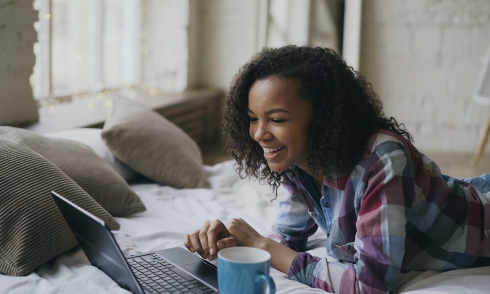 Young woman laughing while looking at laptop on laptop