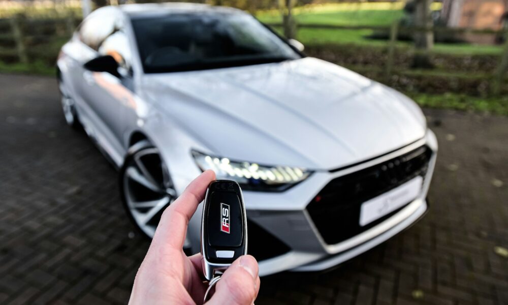 a person holding a car key in front of a silver car