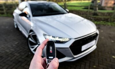 a person holding a car key in front of a silver car