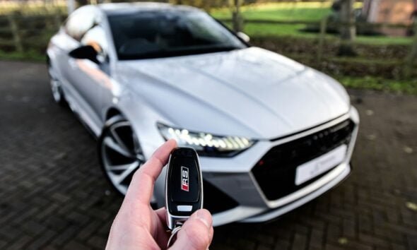 a person holding a car key in front of a silver car