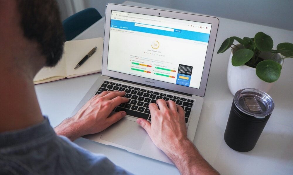 person using macbook pro on white table