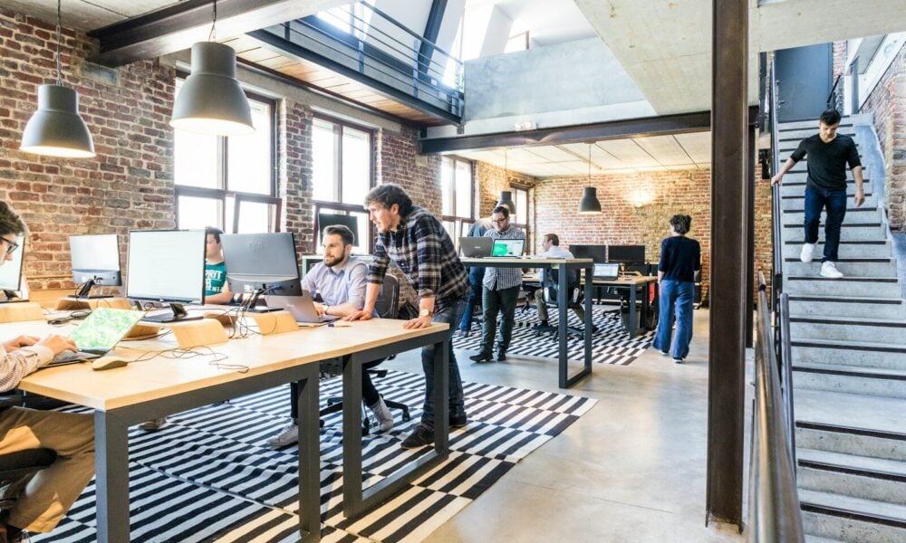 man standing beside another sitting man using computer. Startup Bootstrapped Fundraising Strategy