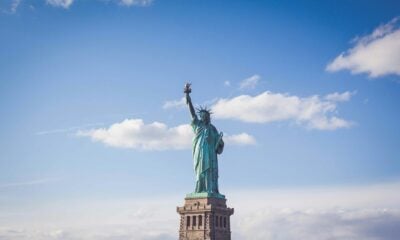 Statue of Liberty, New York under white and blue cloudy skies. Budget Travel Tips for Expensive Cities in the USA