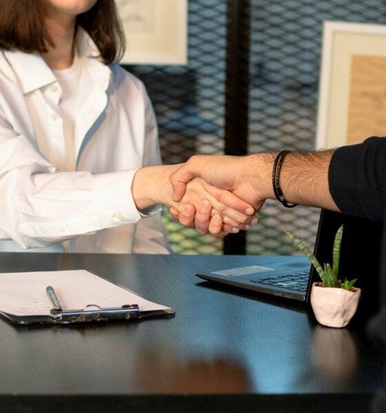 a man and a woman shaking hands in front of a laptop