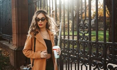 woman in brown coat holding white cup