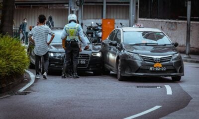 man in white and black stripe shirt and black pants standing beside black car during daytime