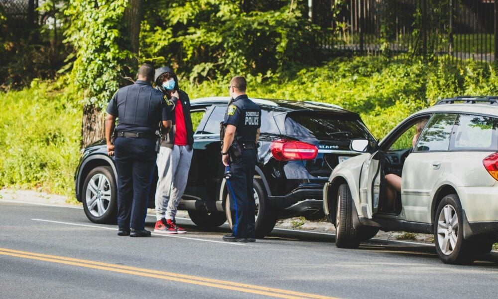 man in black t-shirt and black pants standing beside black suv during daytime