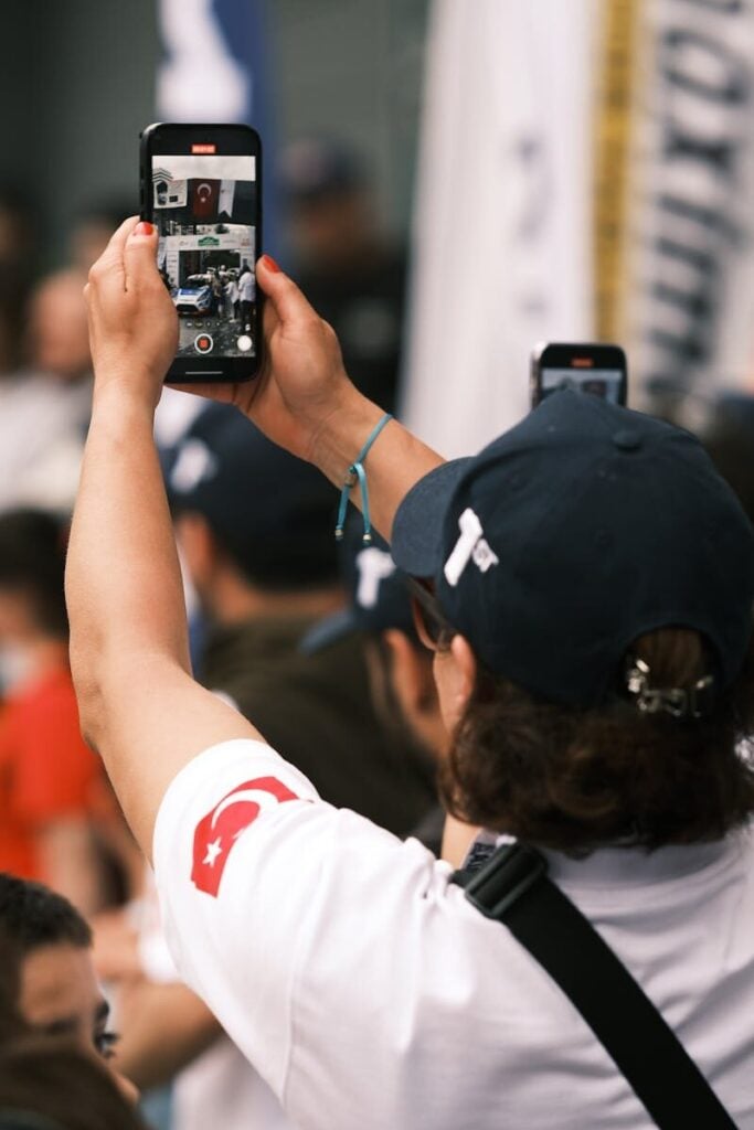 A person records a live event with a phone, capturing the vibrant atmosphere.