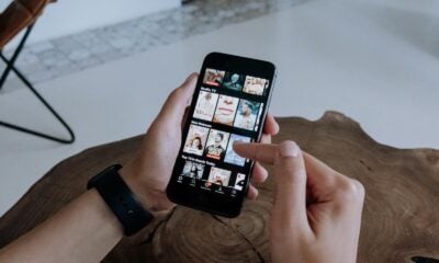 A person using a smartphone to explore and select shows on a streaming platform indoors.