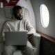 A man wearing headphones uses a laptop in a luxurious airplane cabin.