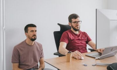 two men sitting at a table with a laptop