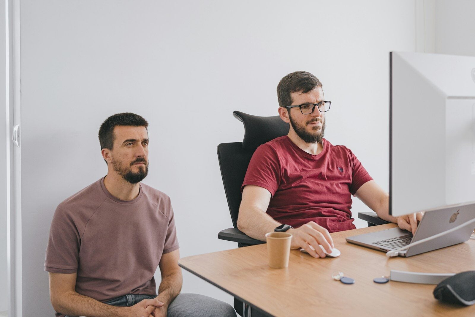 two men sitting at a table with a laptop