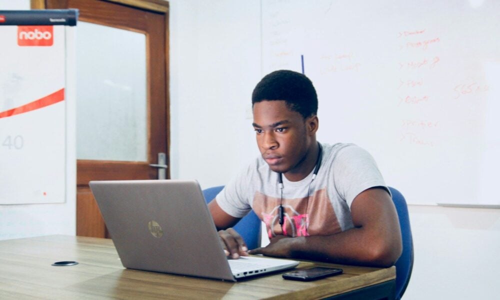 man in grey shirt using grey laptop computer