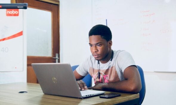 man in grey shirt using grey laptop computer