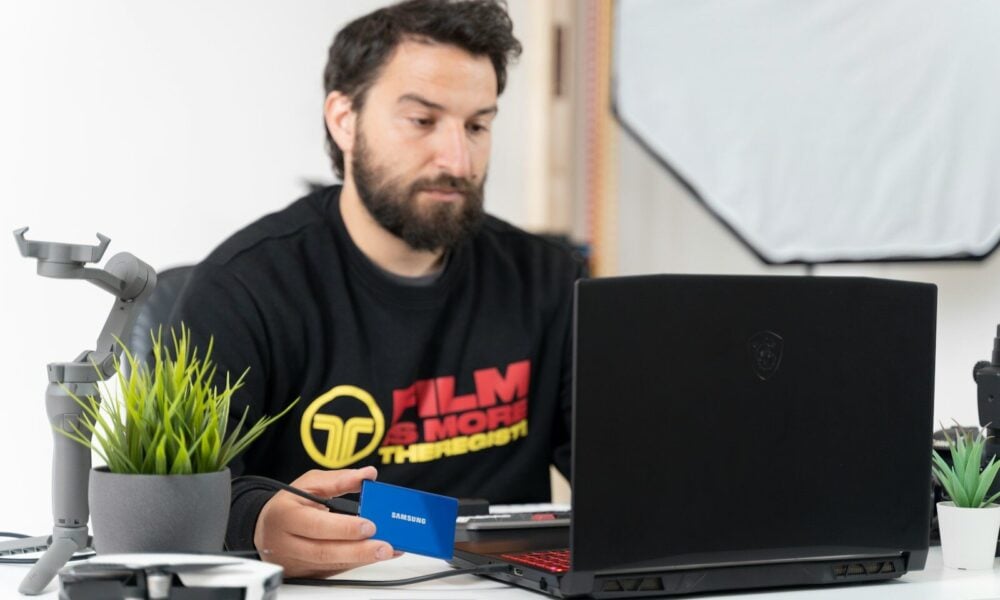 a man sitting at a desk with a laptop and a microphone