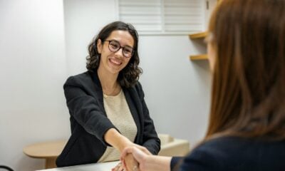 a woman shaking hands with another woman sitting at a table