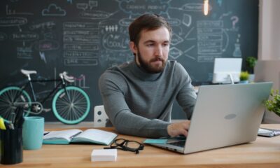 Man working on laptop in office with bicycle.
