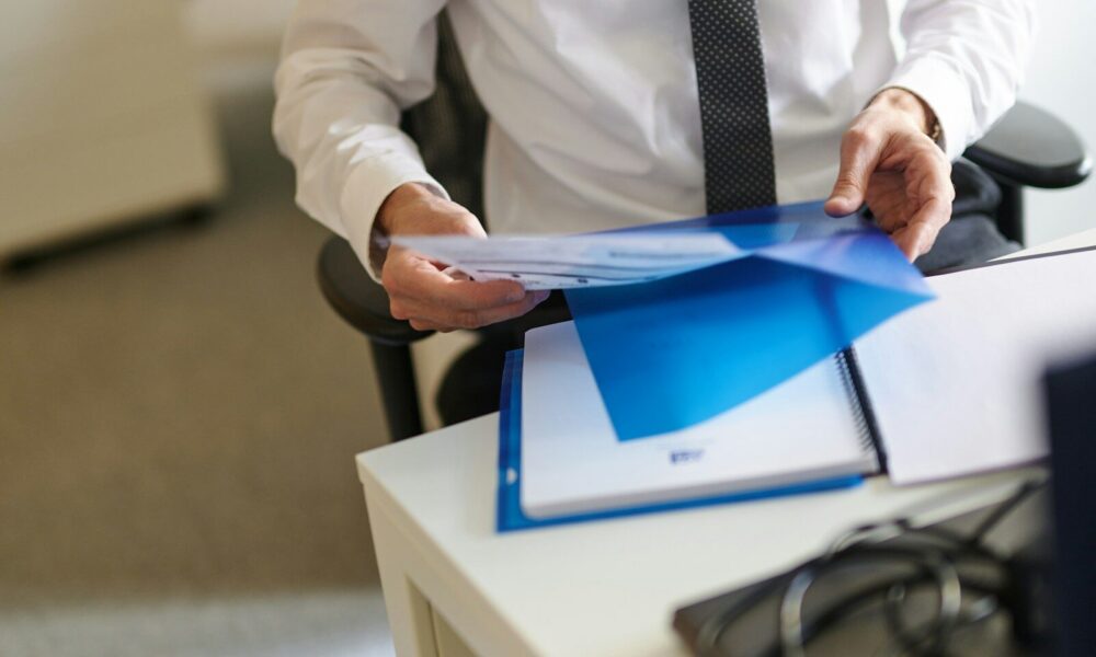 a man in a white shirt and tie holding a folder