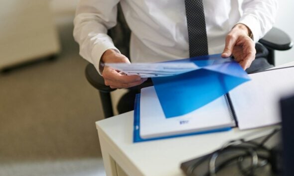 a man in a white shirt and tie holding a folder
