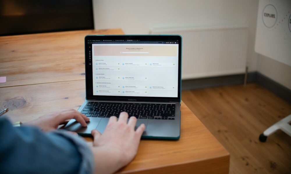 Person typing on a laptop computer on a wooden desk.